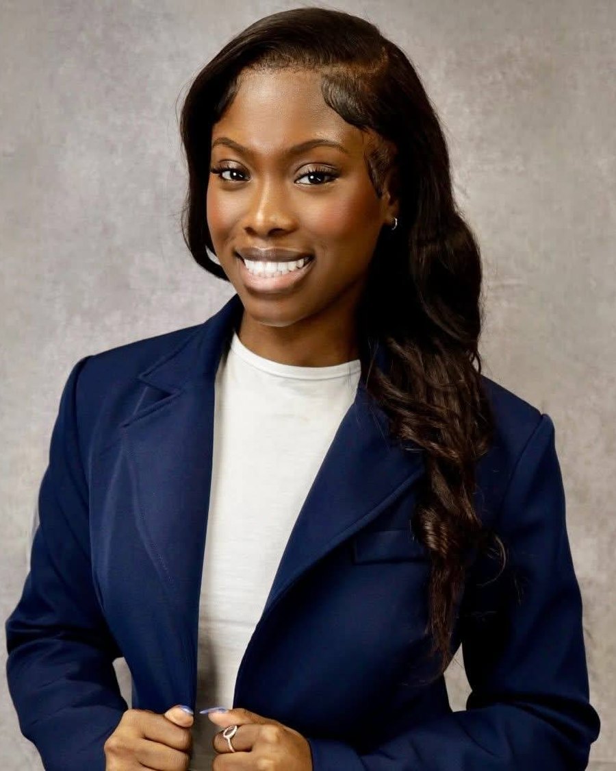 Michele Brutus smiling in a navy blazer and white top